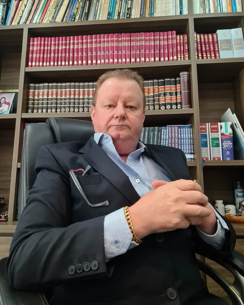 Dr. Edson Antônio Salvador em seu escritório, diante da estante de livros jurídicos